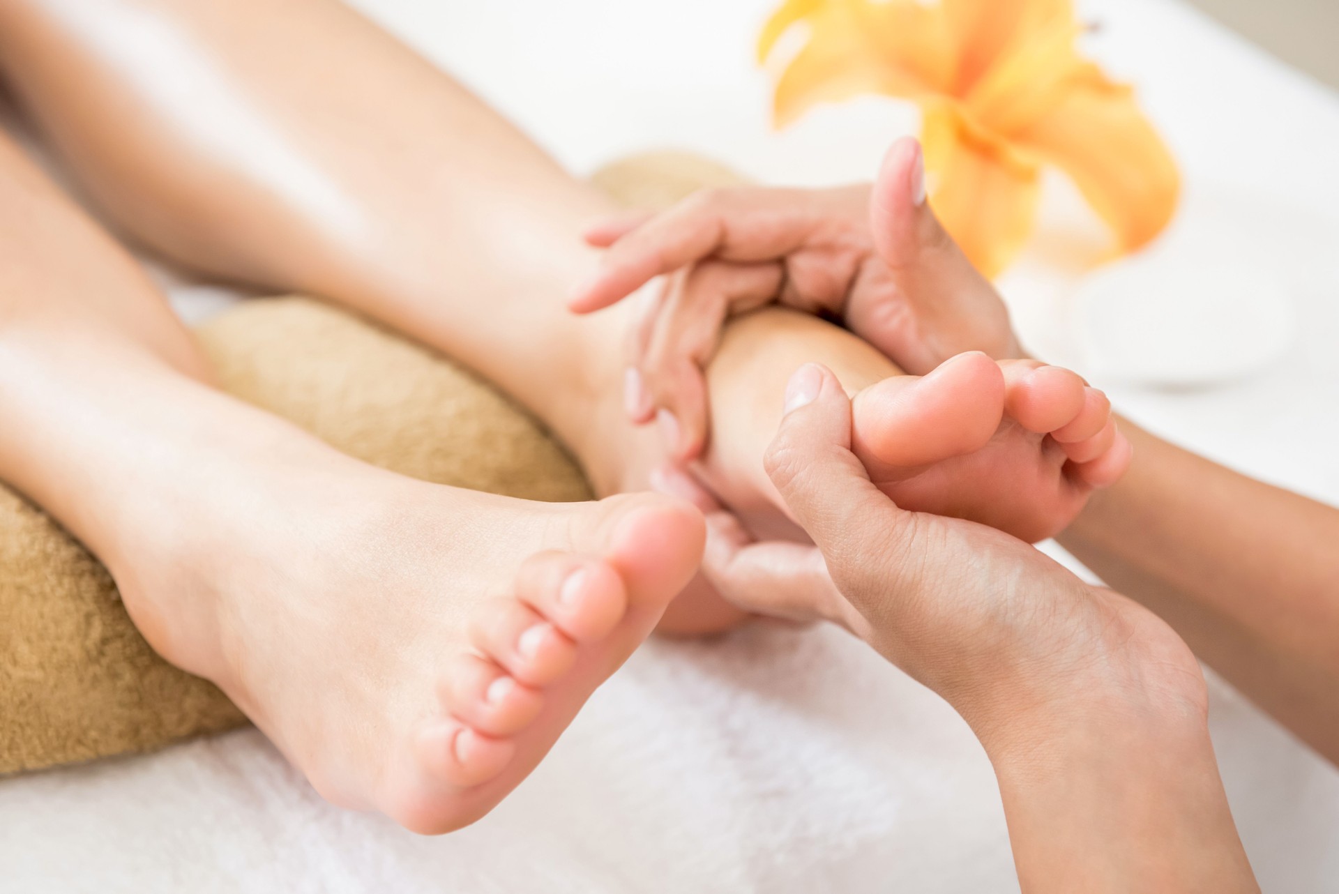 Professional therapist giving relaxing reflexology foot massage to a woman in spa