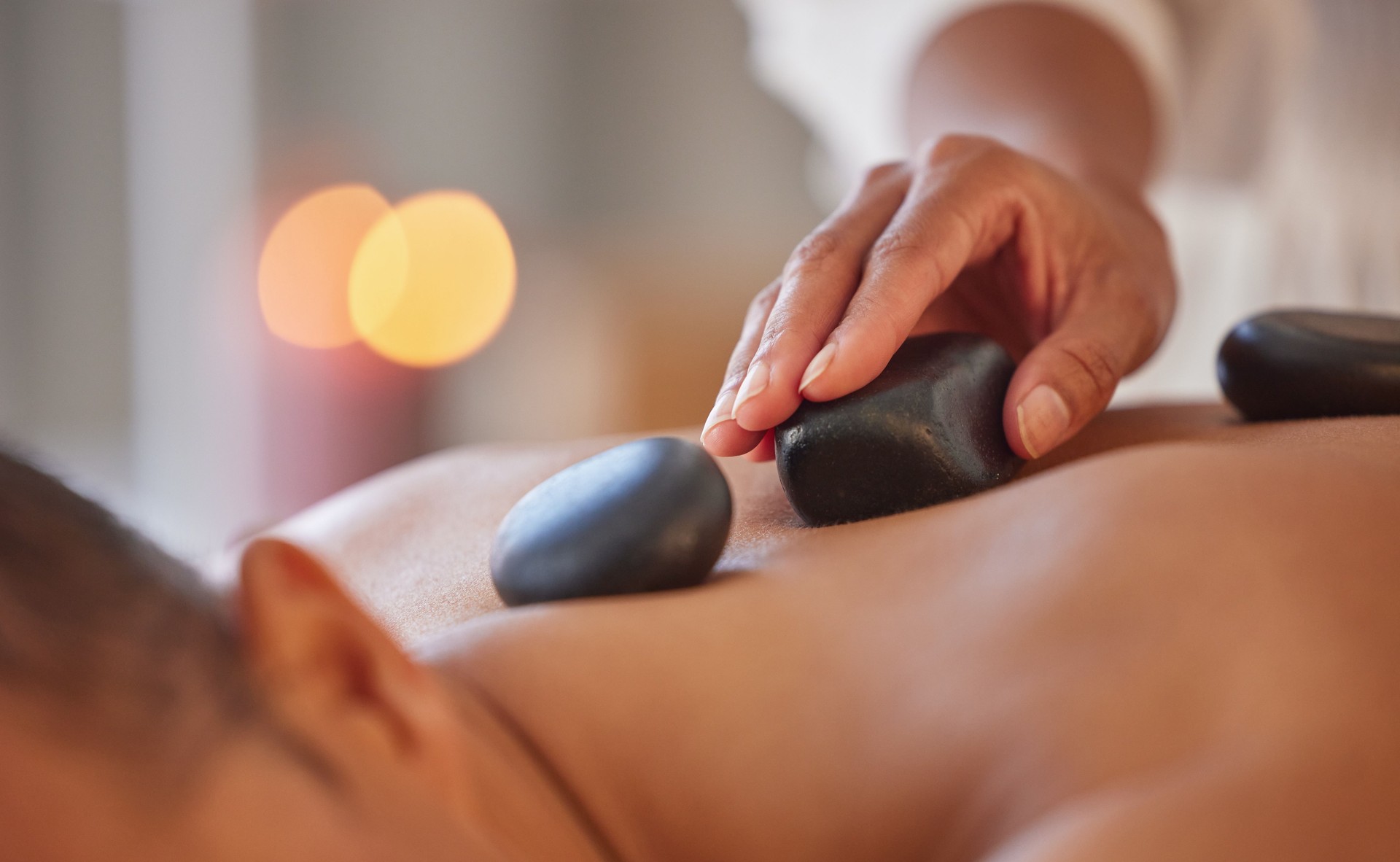 Spa, man and stone massage to relax, wellness and health for body care, peace or holistic care. Male, gentleman or lying on table at luxury resort, zen or therapy for skincare with rocks